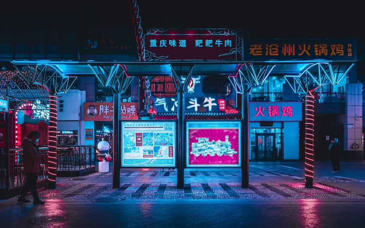 Cyberpunkowa ulica nocą z rozmytymi światłami neonów i futurystyczną platformą w tle.
